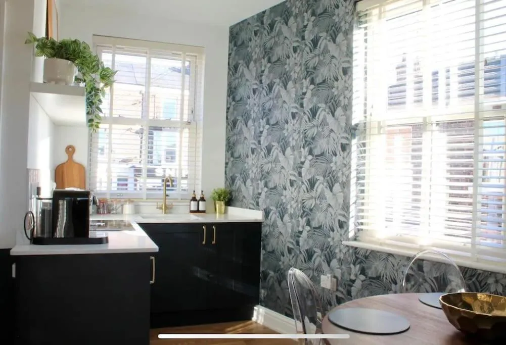 a kitchen with black cabinets and a blue and white wallpaper at Clement House, York, Free EV and parking in York